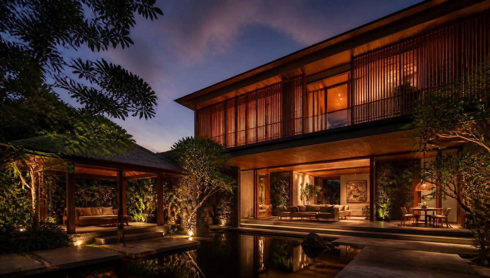 Sunshine house at dusk, timber screens glowing over a courtyard water body