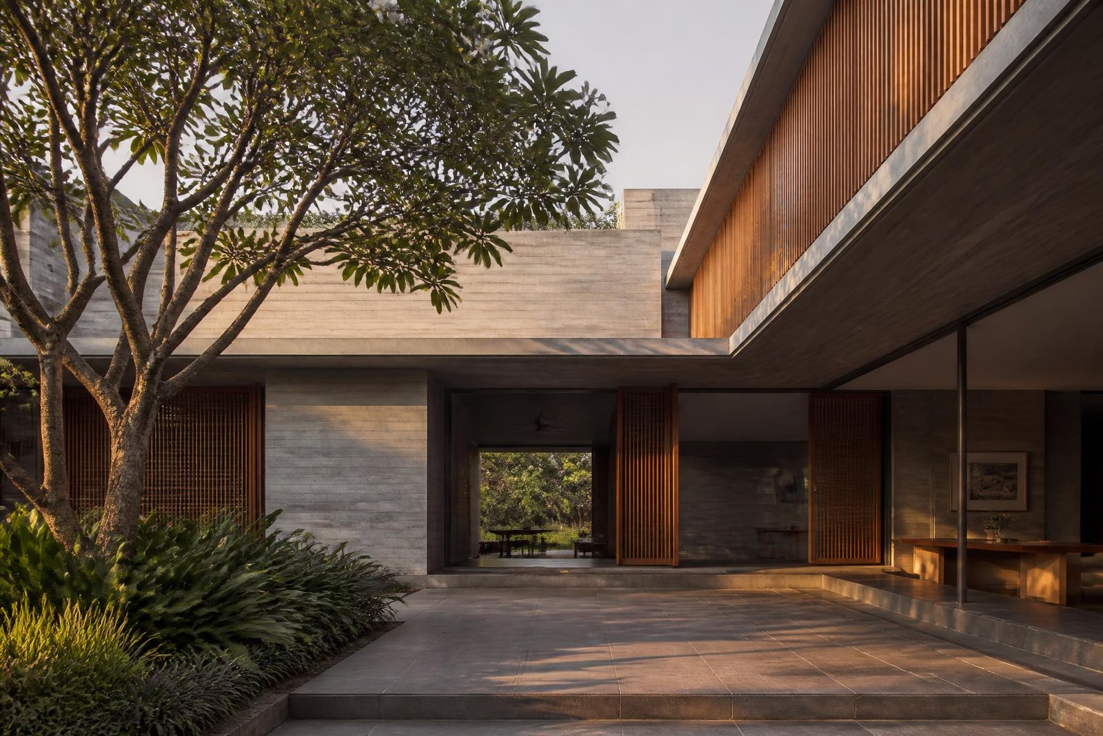 Courtyard of a concrete and teak house in Bengaluru at late afternoon